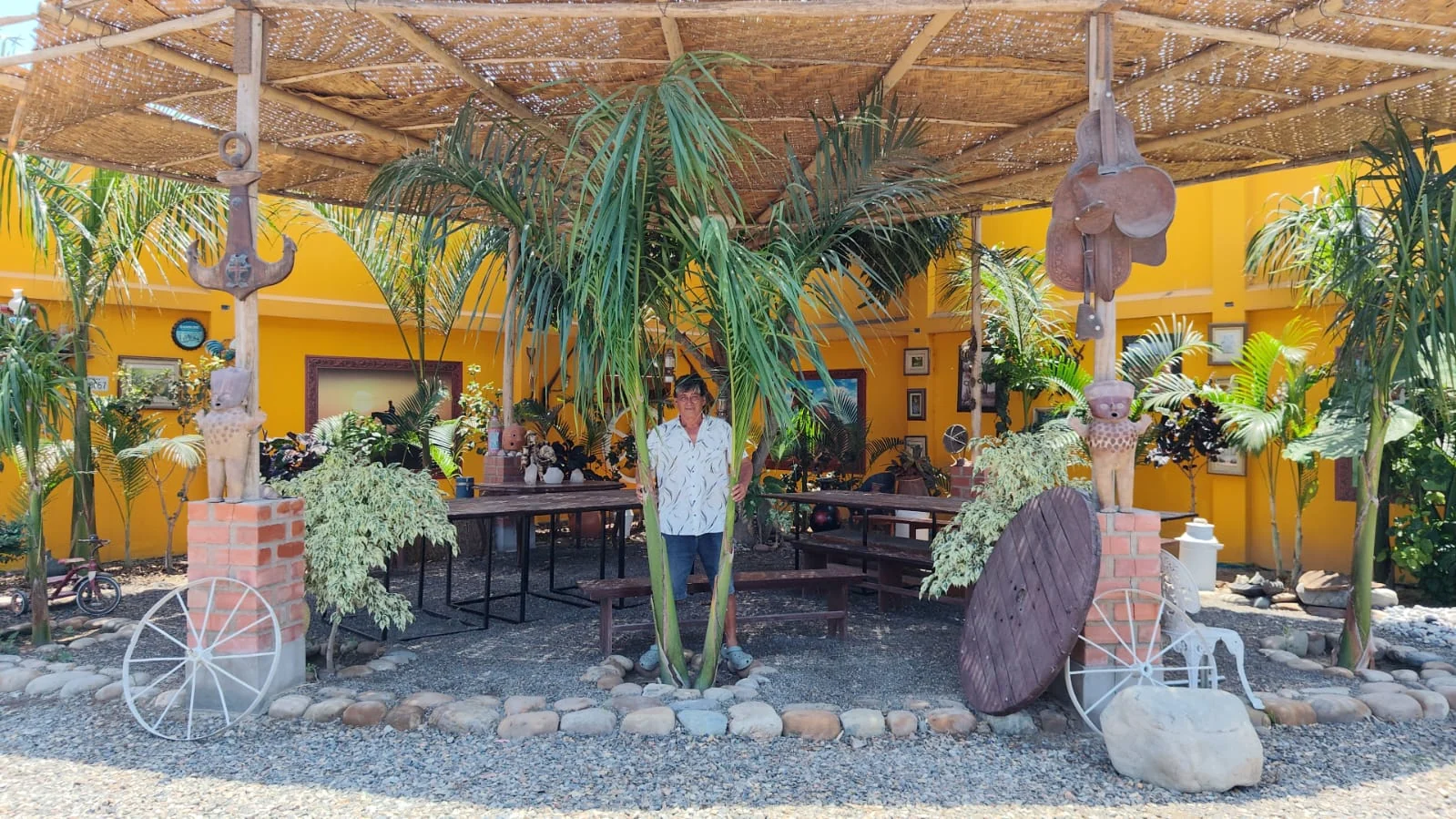 Palmeras y muebles de madera bajo el techo de caña del jardín